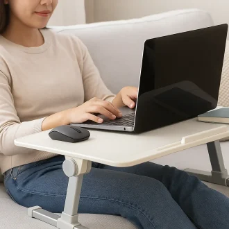 Person using a foldable laptop desk on a couch, demonstrating portable and adjustable workspace setup